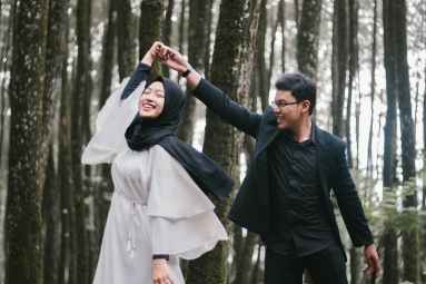 man and woman dancing near forest trees while smiling